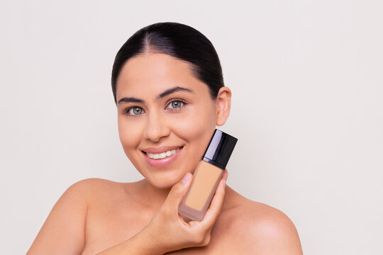 Horizontal portrait of a woman holding a makeup foundation