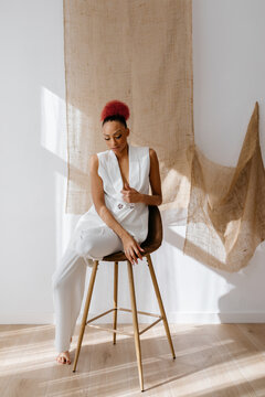 Young female sitting on chair and looking down in light room