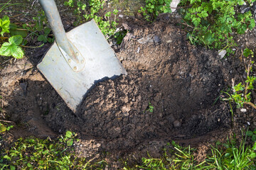 Digging a plant hole in the ground with a spade, brown sandy soil and some weeds around, gardening concept, copy space, copy space, selected focus - 777745172