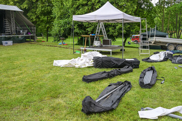 Pavilion for the sound system, tent poles and tarpaulins in bags for setting up an open-air music festival on the meadow, copy space, selected focus