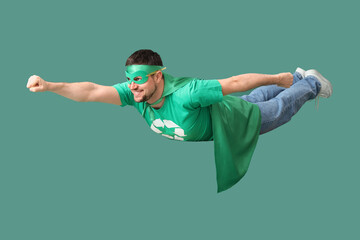 Young man dressed as eco superhero flying on green background. Ecology concept © Pixel-Shot