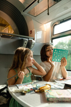 Sibling doing craft during their train ride