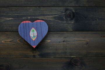 wooden heart with national flag of guam on the wooden background.