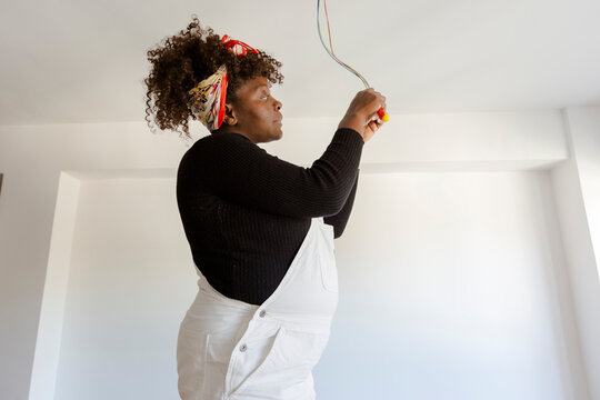 Pregnant woman fixing electric installation in new home