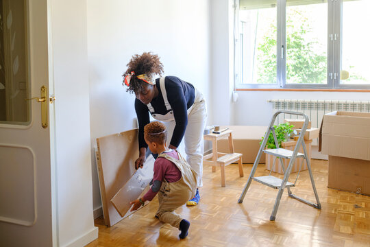 Kid helping his mother moving boxes in new home