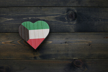 wooden heart with national flag of kuwait on the wooden background.