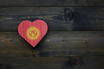 wooden heart with national flag of kyrgyzstan on the wooden background.