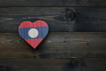 wooden heart with national flag of laos on the wooden background.