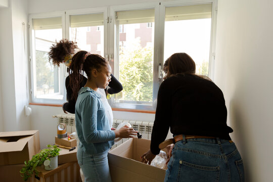 Family unpacking boxes in new home while moving in - Powered by Adobe