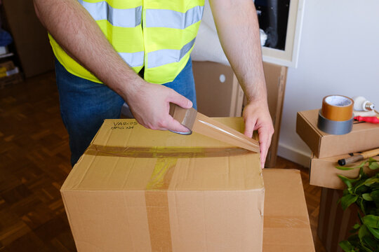 Crop of professional mover's hands moving boxes to new home