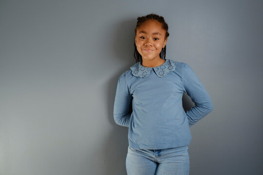 Portrait of 11 year old girl smiling to camera over grey background