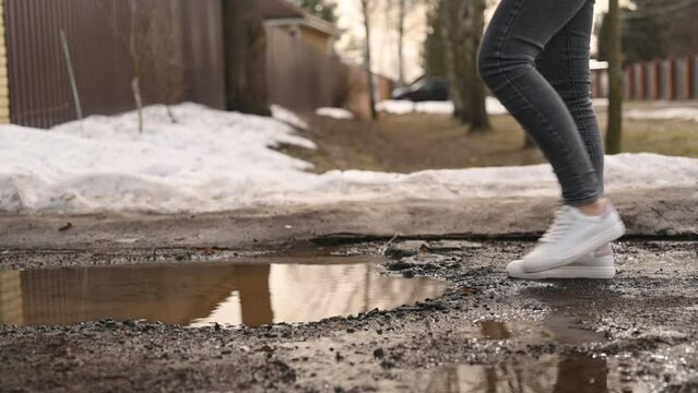 An inattentive woman did not notice the puddle and stepped into it wearing snow-white sneakers