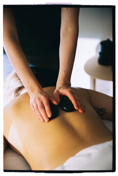 Masseur doing back hot stone massage
