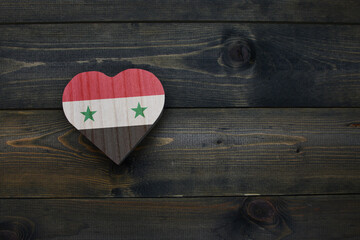 wooden heart with national flag of syria on the wooden background.