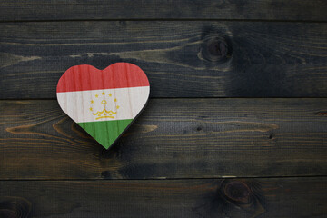 wooden heart with national flag of tajikistan on the wooden background.