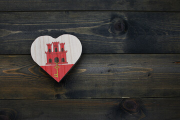 wooden heart with national flag of gibraltar on the wooden background.