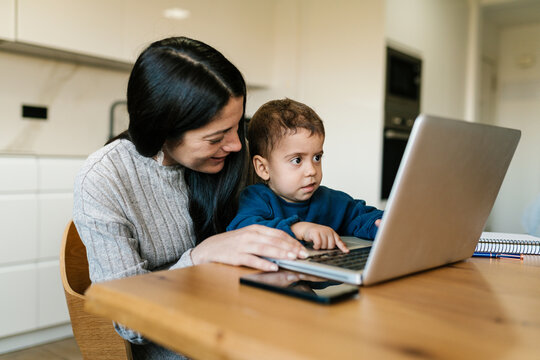 Mother holding son on lap using netbook