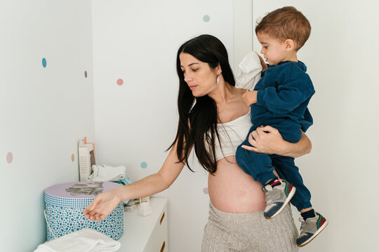 Woman carrying boy and doing housework at home