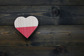 wooden heart with national flag of poland on the wooden background.