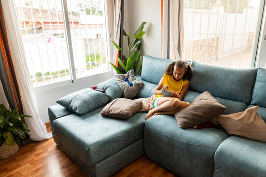 girl looking at tablet on sofa