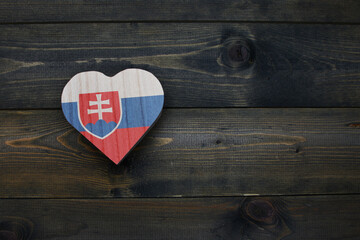 wooden heart with national flag of slovakia on the wooden background.