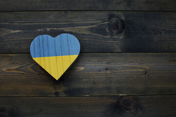 wooden heart with national flag of ukraine on the wooden background.