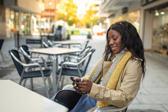 black woman using mobile phone sitting in a cafe