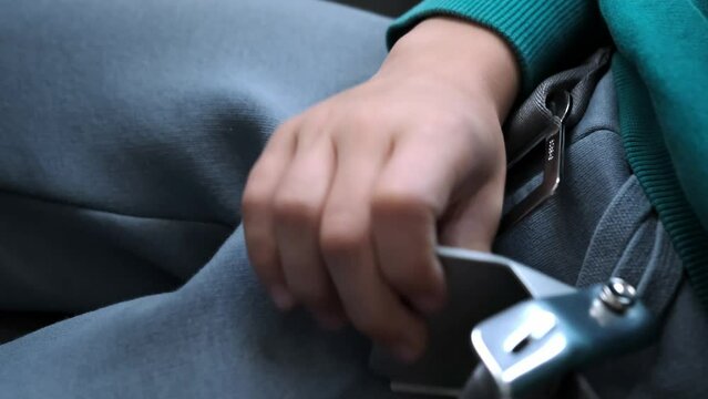 A child passenger unfastens a seatbelt on the airplane after takeoff and landing. A kid buckles off or unlock buckle the seat belt on plane close-up. Concept of safe traveling by air. Safety rules.