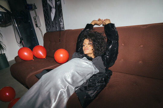 Chic Woman Lounging on Sofa with Balloons Post-Party