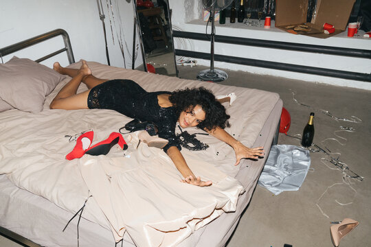 curly woman laying on bed among shoes