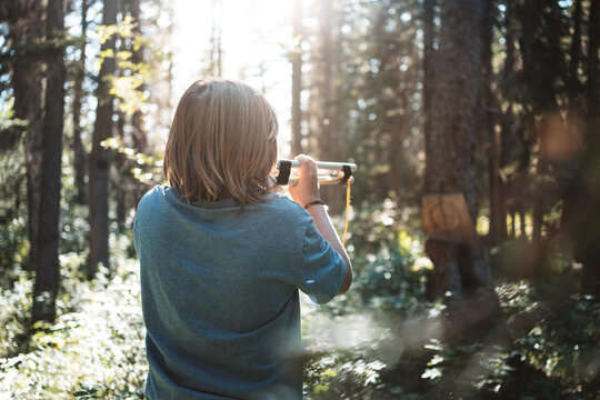 boy playing with blowpipe in the woods