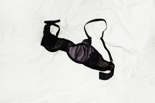 Black transparent mesh bra / lingerie laying on bed with bedsheets