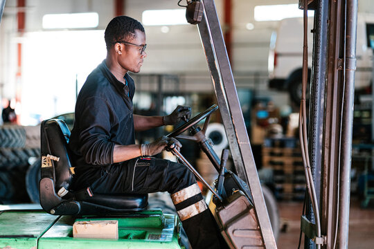 Professional male operator moving tires in warehouse