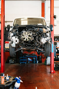Suspended car with opened bonnet showing engine and wheel in garage