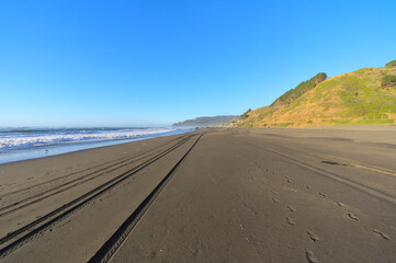 Deserted sand beach at sunset during windy summer day on pacific ocean (Iloca, Chile)