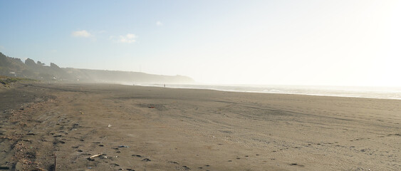 Deserted sand beach at sunset during windy summer day on pacific ocean (Iloca, Chile)