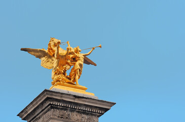 Golden statue with winged horse and female musician at the Alexander III bridge in  Paris, France with clear blue sky