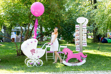 woman in a photo zone with a stroller and balloons with children's toys. photo zone in baby park © Svetlana