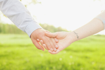 close up of man and woman hands on green garden background, summer day for love and care concept