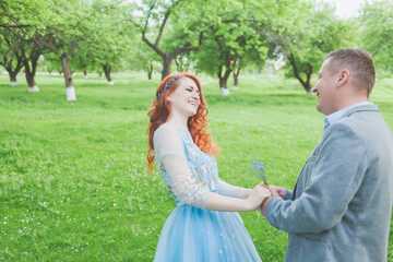 close-up of a man and woman holding hands on a blurred background on a summer day for the concept of love and care. blue spring flowers in hands