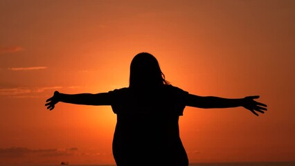  A girl makes a v sign with her hands as a sign of victory at sunset