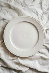 An empty white plate on a crumpled grey fabric background