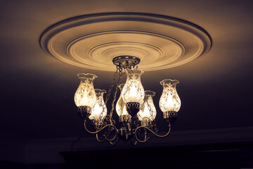Chandelier in dark room. The glass chandelier shades are tulip-shaped.