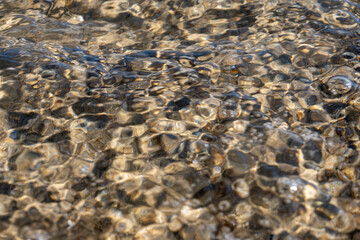 Crystal clear sea water texture with glare from the sun, wallpaper