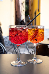 Aperol and Campari Spritz orange bitter long drink cocktails made with liqueur, prosecco sparkling wine, ice cubes and piece of orange, Milan, Italy