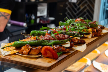 Wooden plate with Turkish mixed grill meat, chicken wings, lamb, beef shashlik, kebab, peppers from charcoal grill in restaurant