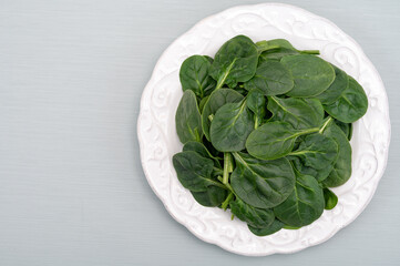 Fresh green baby Spinach leaves, diet and health concept, weight loss, spinach on ceramic plate, copy space