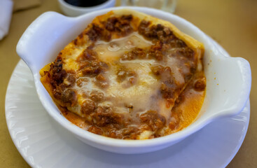 Traditional first course for lunch or dinner in Italy, lasagne Bolognese with beef meat and bechamel sauce served in Italian restaurant, Milan, Italy