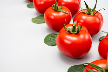Food ornament, Red ripe tasty Dutch tomatoes and spinach leaves, vegetables background top view close up copy space