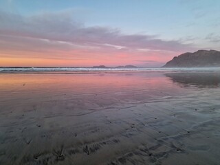 Sunset on Famara Beach, Lanzarote, casts a mesmerizing palette of colors across the sky, blending hues of orange, pink, and purple against the backdrop of the Atlantic Ocean waves.